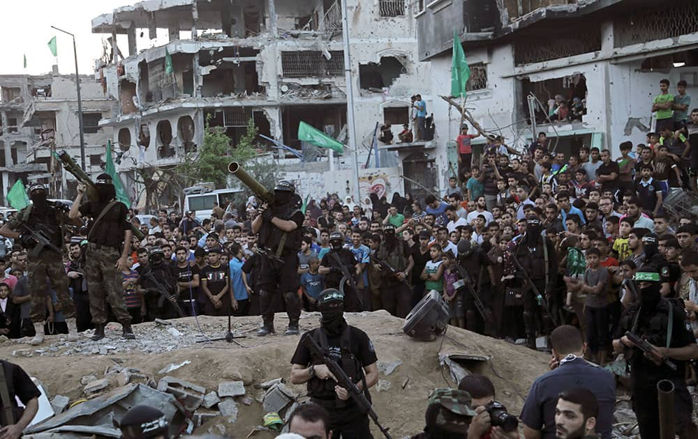 Palestinian masked militants of Izzedine al-Qassam Brigades, military wing of Hamas, hold their weapons during celebration of the victory rally at the debris of destroyed houses in Shijaiyah, neighborhood of Gaza City, in the northern Gaza Strip.