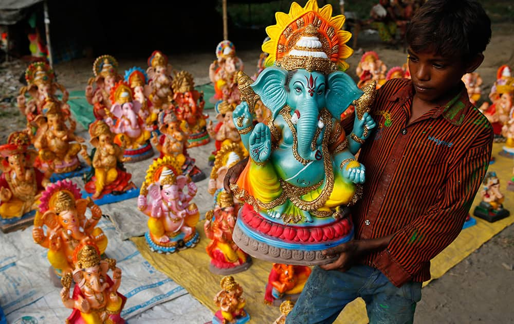 A boy carries an idol of Hindu god Ganesh as he displays them for sale in Allahabad.