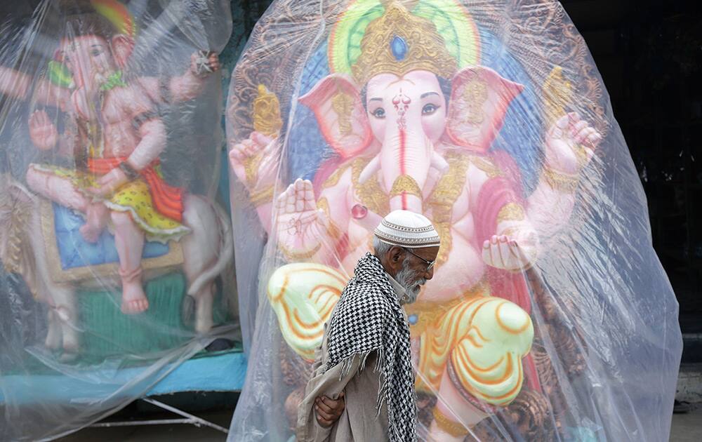 A Muslim man walks past idols of Hindu God Ganesha displayed for sale ahead of the Ganesh Chaturthi festival in Hyderabad.