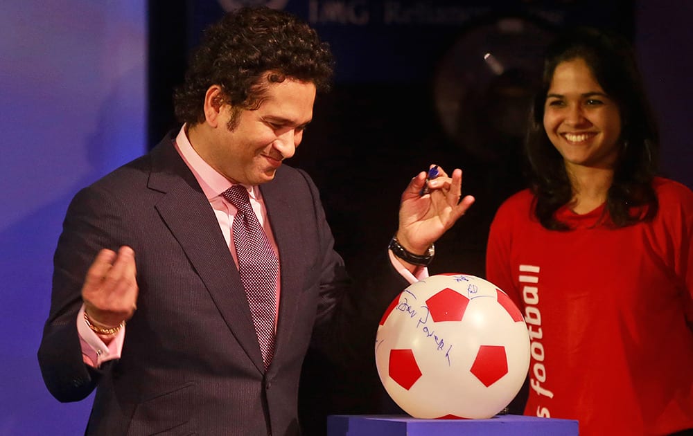 Sachin Tendulkar, former Indian cricketer and co-owner of Kerala Blasters Football Club, signs a soccer ball during official launch of the Indian Super League (ISL) in Mumbai.