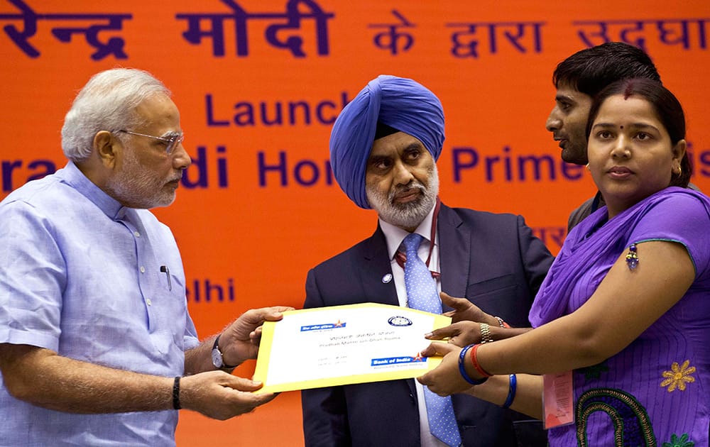 Prime Minister Narendra Modi hands over a banking kit to an unidentified woman at the launch of a campaign aimed at opening millions of accounts for poor Indians in New Delhi.