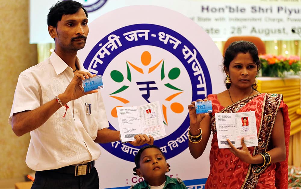 A couple displays their newly received debit cards and bank passbooks, during the launch of a massive countrywide campaign to open millions of accounts for the poor in Mumbai.