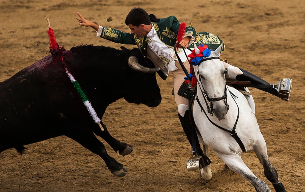 Bullfighter Joao Moura rides on his horse as he places a banderilla on the back of a Castillejo de Huebra fighting bull during a horseback bullfight at the running of the bulls Sanse festival, in San Sebastian de los Reyes, Spain.