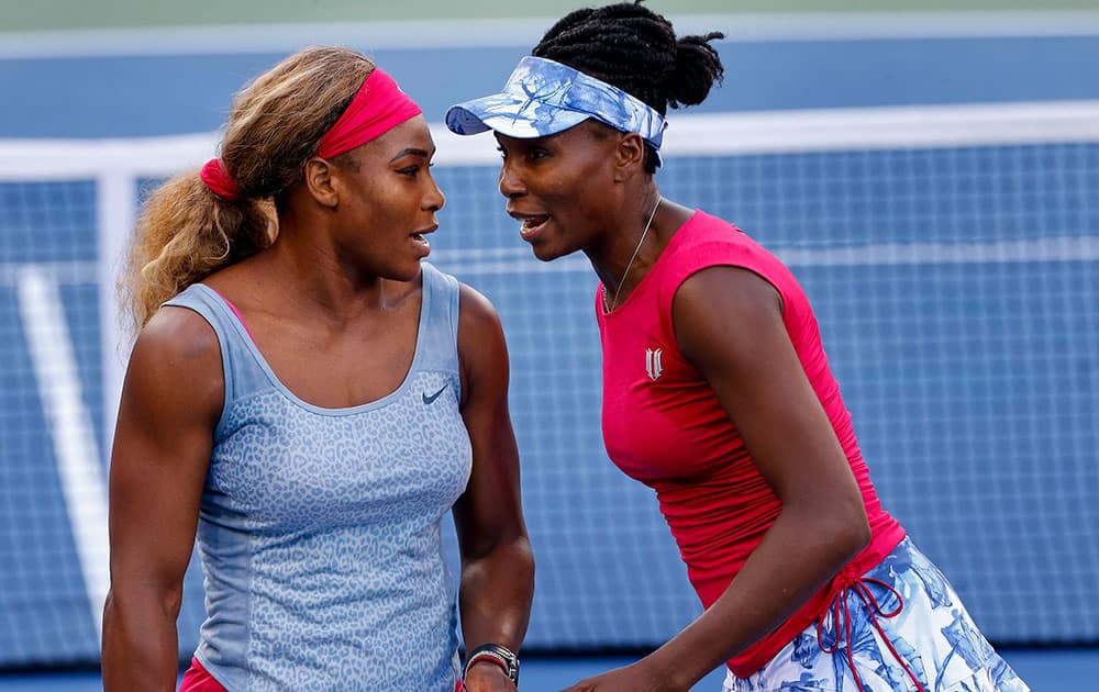 Serena Williams, left, and Venus Williams talk between points against Timea Babos and Kristina Mladenovic during a doubles match at the 2014 US Open tennis tournament.