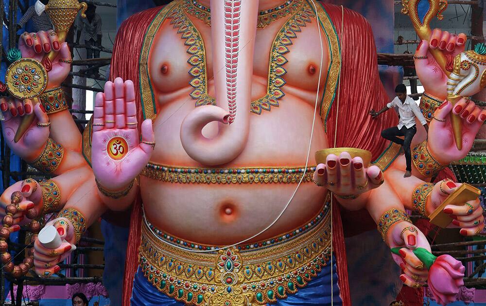 A man climbs a 60 feet idol of Hindu god Ganesha to decorate it in preparation for the upcoming Ganesh Chaturthi festival in Hyderabad.