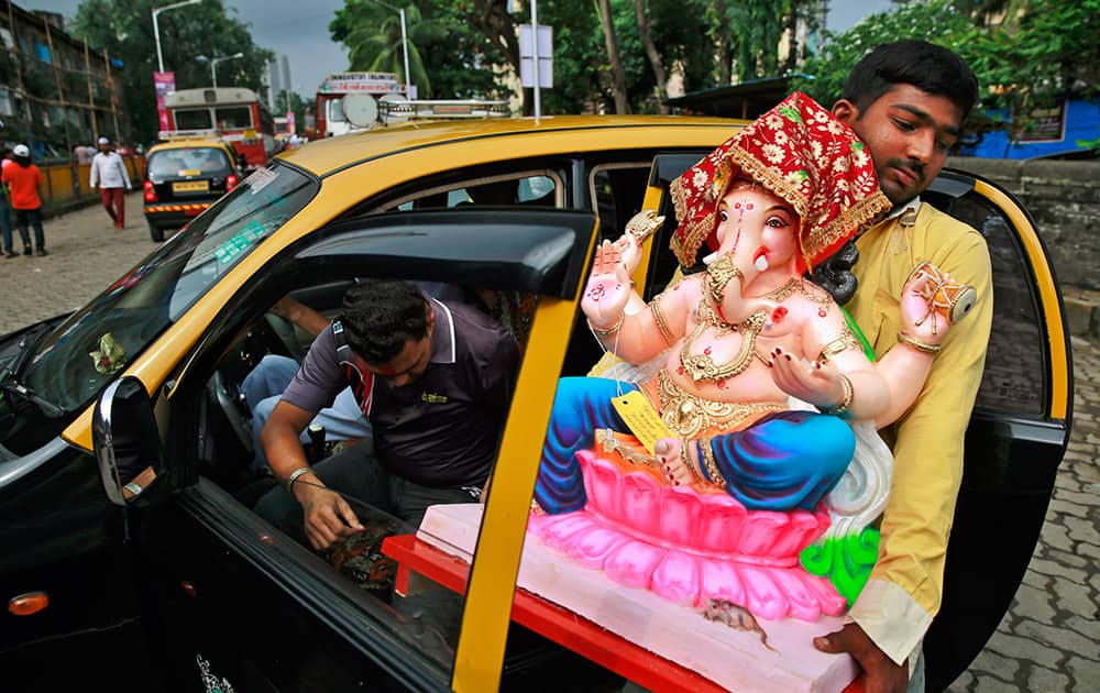 A Hindu devotee carries a clay idol of Hindu god Ganesha into a taxi during Ganesh Chaturthi festival in Mumbai.