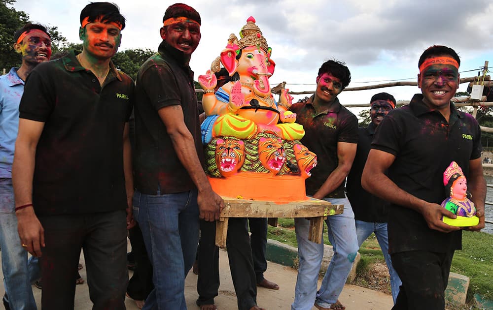 Hindu devotees, faces smeared with colored powder, carry a clay idol of Hindu god Ganesha to immerse in a lake on the first day of Ganesh Chaturthi festival in Bangalore.