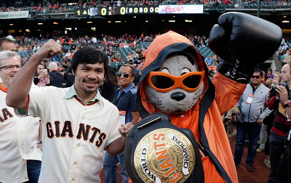 Boxer Manny Pacquiao, poses for pictures with San Francisco Giants mascot Lou Seal before Pacquiao was to throw the ceremonial first pitch before a baseball game between the Giants and Milwaukee Brewers in San Francisco.