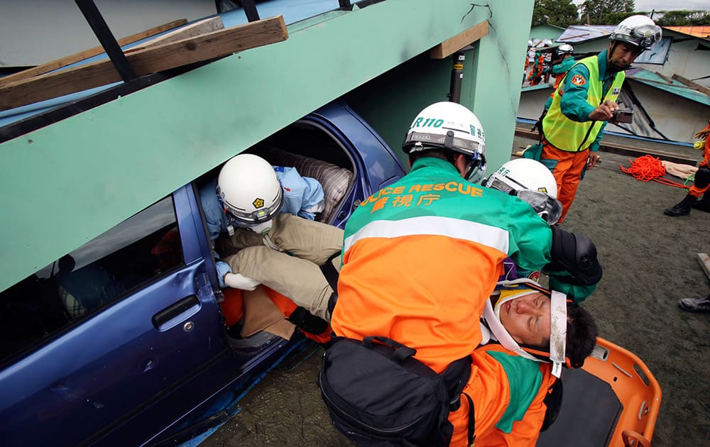 Tokyo Metropolitan Police members rescue a person playing the roll of an injured person from a damaged car during an annual disaster drill in Tokyo.