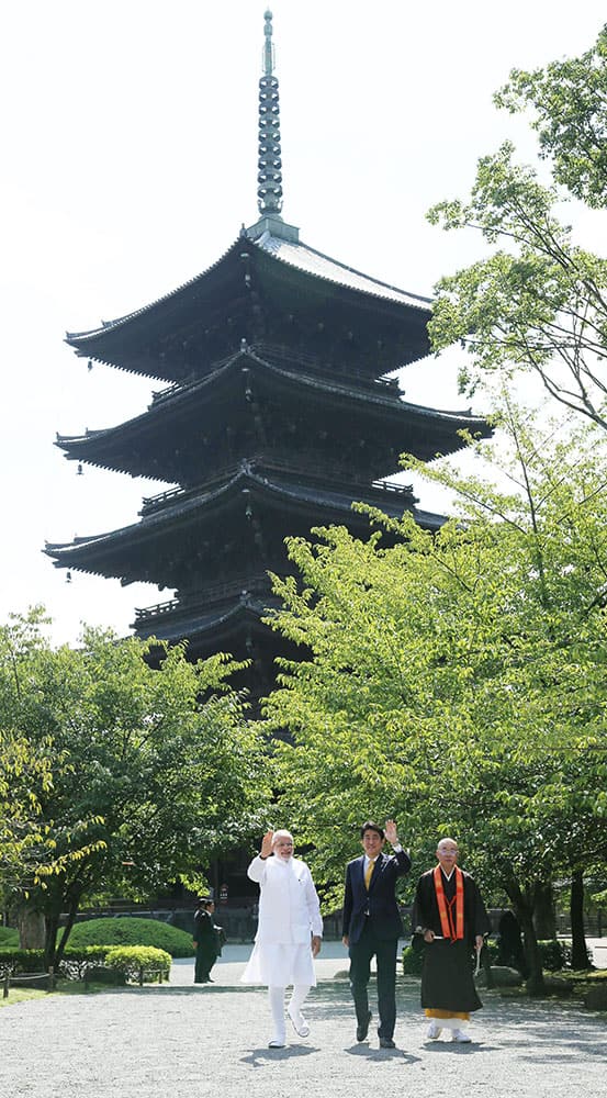 Indian Prime Minister Narendra Modi, left, and his Japanese counterpart Shinzo Abe, center, wave in front of the five-story stupa at Toji Temple in Kyoto, western Japan.