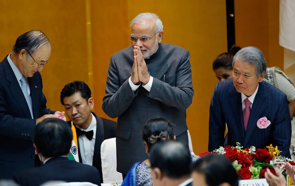 Indian Prime Minister Narendra Modi greets business leaders after giving a speech and returning to his seat as Chamber of Commerce and Industry Chairman Akio Mimura, left, and Japan Federation of Economic Organizations Chairman Sadayuki Sakakibara, right, greet him during a luncheon hosted by Japan Business Federation in Tokyo.