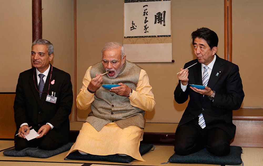 INDIA'S PRIME MINISTER NARENDRA MODI, CENTER, AND JAPANESE PRIME MINISTER SHINZO ABE, RIGHT, EAT TEA CAKES DURING A TEA CEREMONY AT A TEA HUT OF THE OMOTESENKE, ONE OF THE MAIN SCHOOLS OF JAPANESE TEA CEREMONY, IN TOKYO.