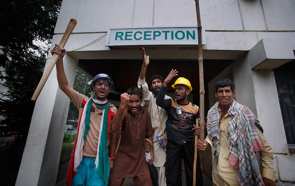 Pakistani protesters hold sticks and chant slogans after intruding the state television building in Islamabad, Pakistan.