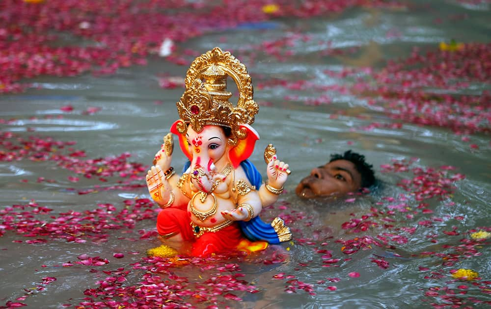 A devotee carries an idol of Hindu God Ganesha for immersion in a water body on the second day of the ten-day Ganesh festival in Mumbai.