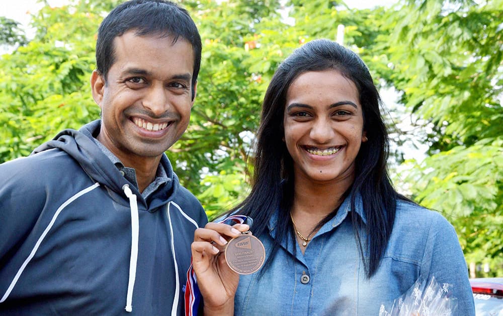 Shuttler P V Sindhu showing bronze medal which she won at World Badminton Championship in Copenhagen, on her arrival at Shamshabad Airport in Hyderabad on Tuesday. Her coach P Gopichand is also seen.