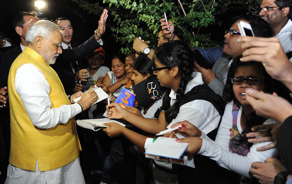 Prime Minister Narendra Modi signing autographs for children during inauguration of the Vivekananda Cultural Centre at the Indian embassy in Tokyo, Japan.