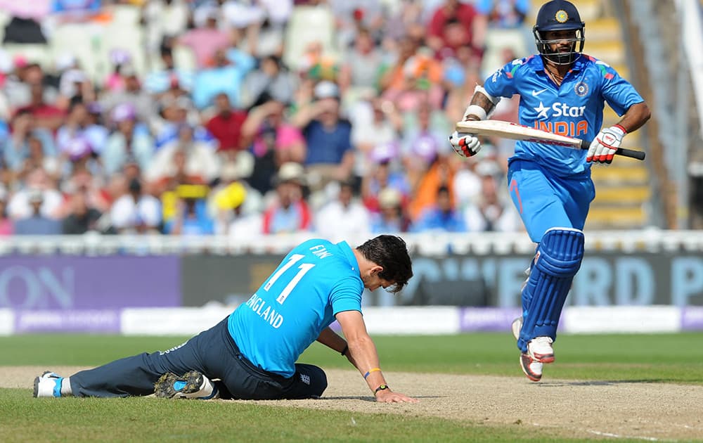 England's Steven Finn on the floor as India's Shikhar Dhawan runs between wickets during the fourth One Day International match between England and India at Edgbaston cricket ground, Birmingham, England.