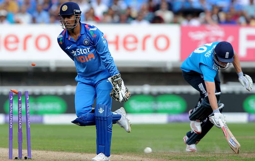 England's Chris Woakes is run out for 10 runs watched by India's wicket keeper and captain M S Dhoni during the fourth One Day International match between England and India at Edgbaston cricket ground, Birmingham, England.