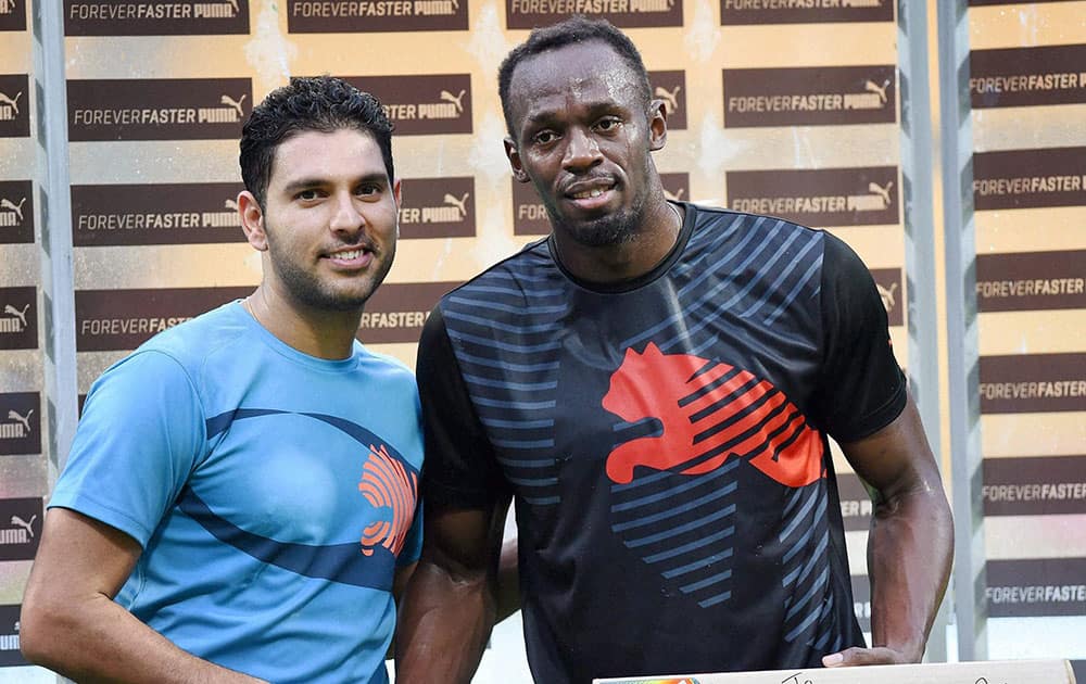 Cricketer Yuvraj Singh presents a bat signed by him to Olympic Gold Medalist sprinter Usain Bolt in the sidelines of a friendly cricket match in Bengaluru.