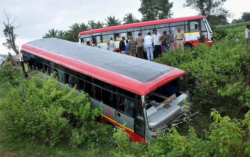 People standing near a bus that slided off the road near a lake at Chikmagalur in Karnataka.