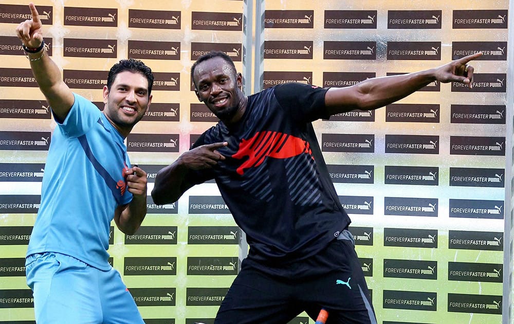 Olympic Gold Medalist sprinter Usain Bolt strikes his trademark pose with cricketer Yuvraj Singh during a friendly cricket match in Bengaluru.