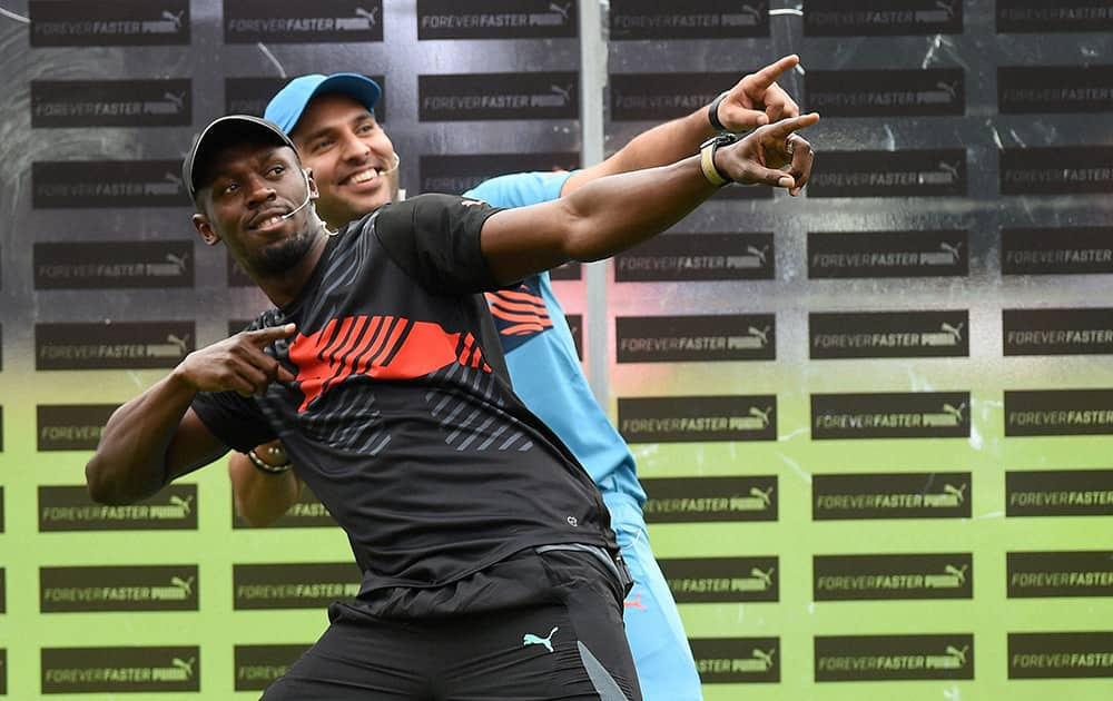 Olympic Gold Medalist sprinter Usain Bolt strikes his trademark pose with cricketer Yuvraj Singh during a friendly cricket match in Bengaluru.