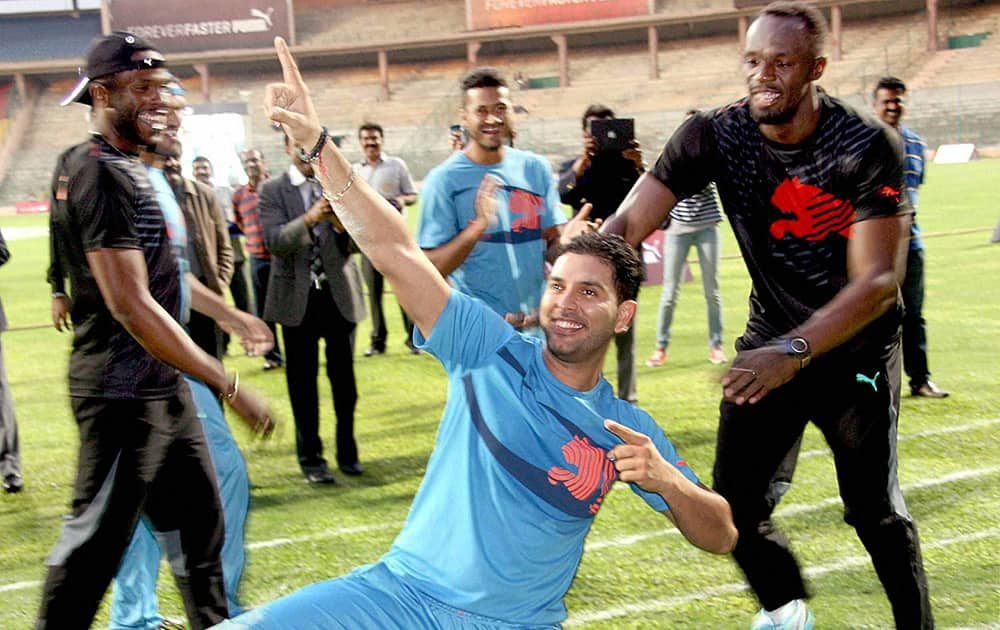 Olympic Gold Medalist sprinter Usain Bolt looks on as cricketer Yuvraj Singh strikes his trademark pose during a friendly cricket match in Bengaluru.