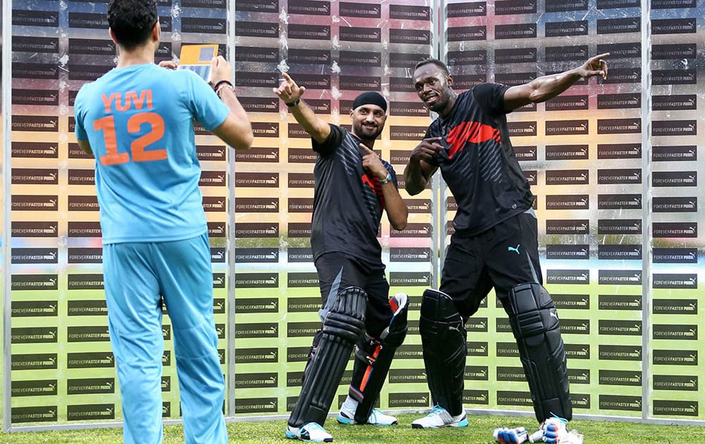 Olympic Gold Medalist sprinter Usain Bolt strikes his trademark pose with cricketer Harbhajan Singh as Yuvraj Singh takes their picture during a friendly cricket match in Bengaluru.