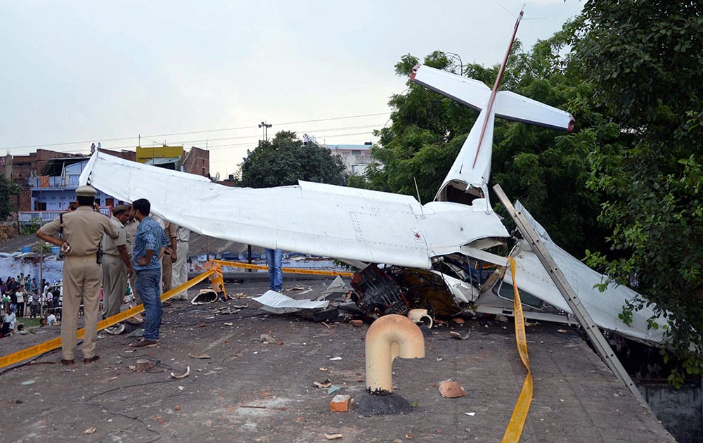 Police men inspect after a glider crashed on the roof of a building in a colony at Babu Purwa in Kanpur.