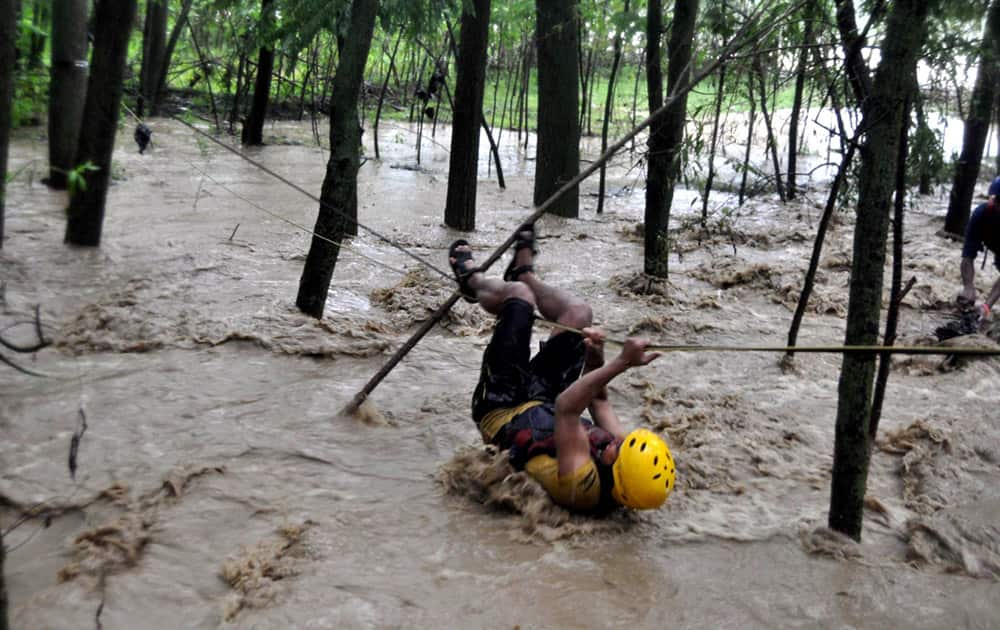A youth attempts to move at safer place using a rope at Akran Nowpora in Kulgam after heavy rains deluged nearby villages.