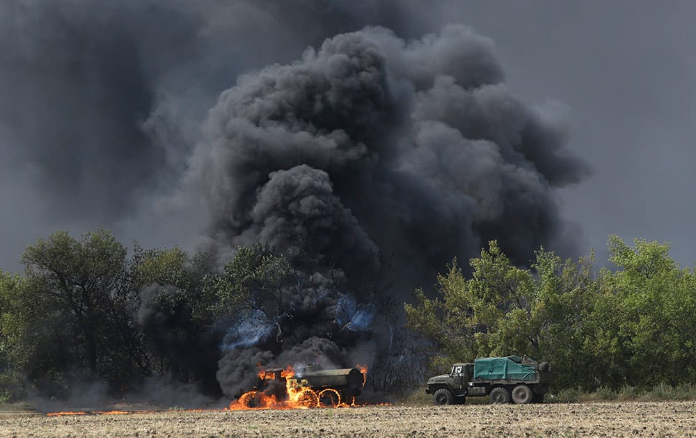 An unmarked military vehicle burns on a country road in the village of Berezove, eastern Ukraine.
