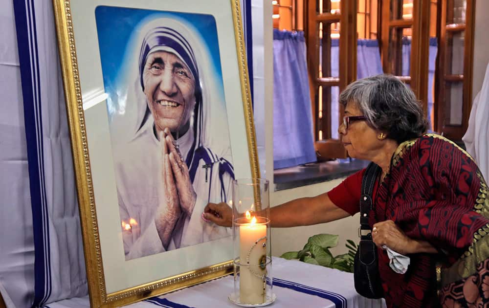 A Catholic woman offers prayers as she touches a portrait of Mother Teresa on her 17th death anniversary at the Missionaries of Charity in Kolkata.