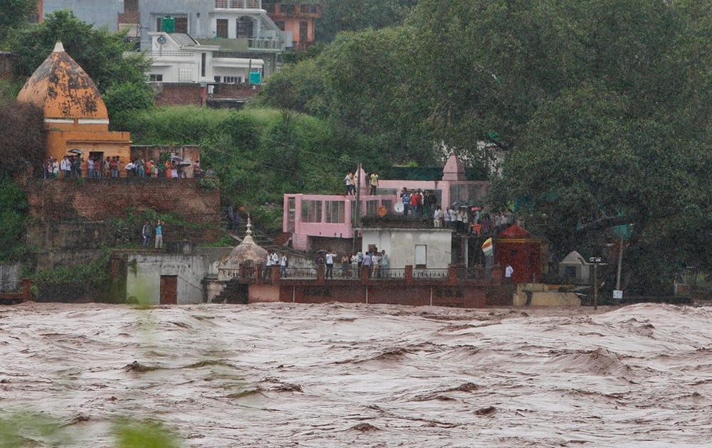 Residents watch the overflowing Chenab River after heavy rains, at Akhnoor, about 30 kilometers (19 miles) northwest of Jammu.