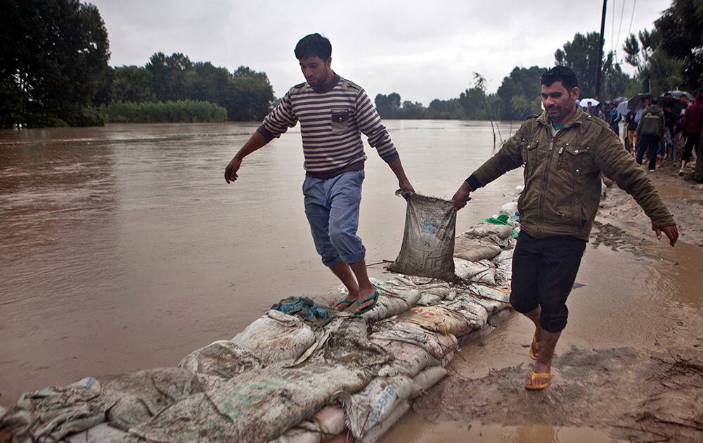 Kashmiri Muslims carry sand bags to keep out floodwaters in Srinagar.
