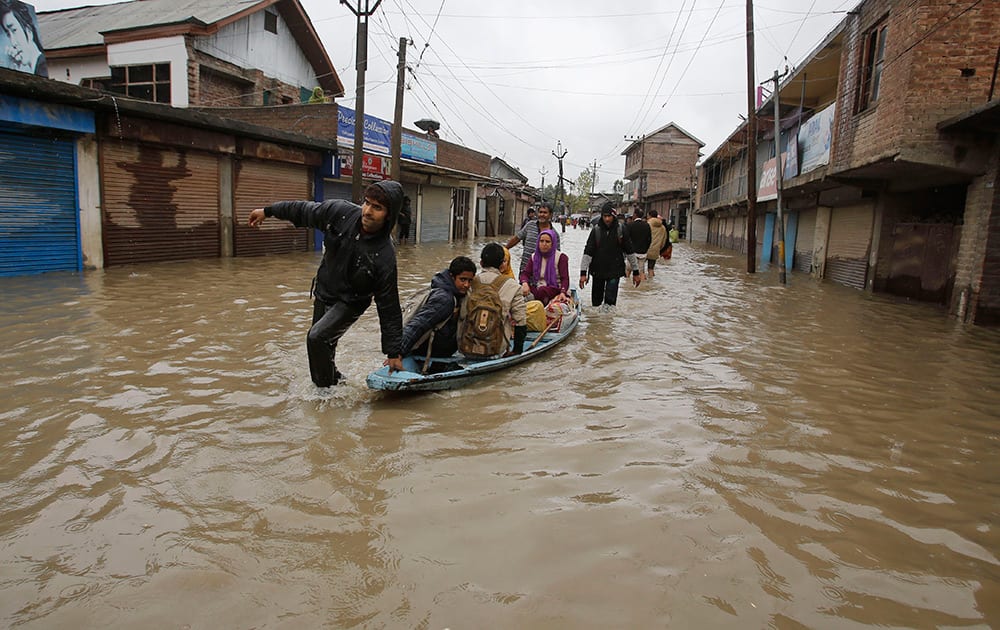 Kashmiris cross a flooded neighborhood on a boat in Srinagar.