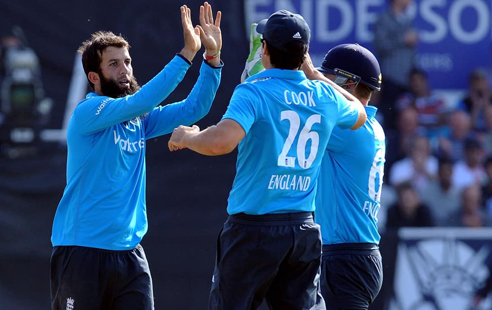 England's Moeen Ali celebrates with Alastair Cook and Jos Buttler after bowling India's Shikhar Dhawan for 31 runs during the fifth One Day International match between England and India at Headingley cricket ground, Leeds, England.