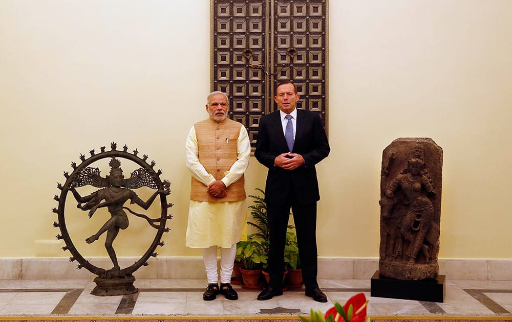 Prime Minister Narendra Modi and his Australian counterpart Tony Abbott stand between a bronze Nataraja idol and stone Shiva idol in New Delhi.