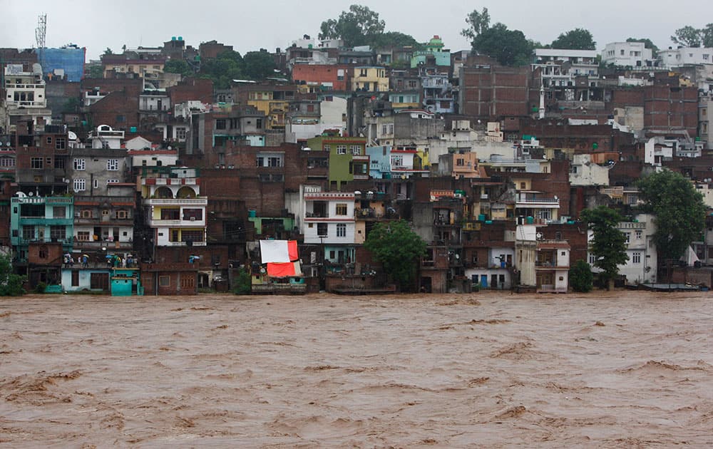 People watch the swelling River Tawi from the roof of their houses in Jammu.