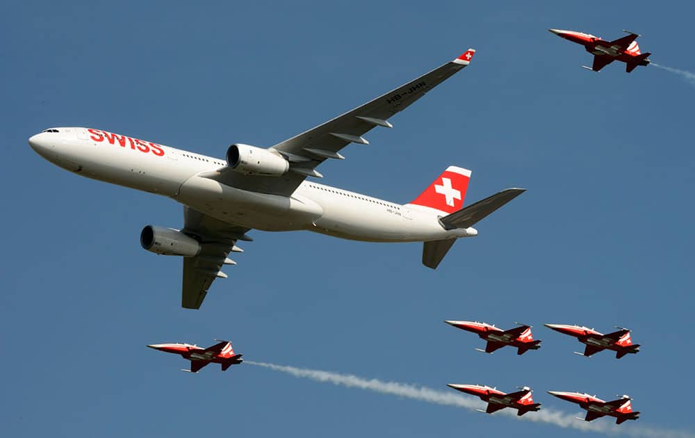 Escorted by six Tiger F5-E jets of the Patrouille Suisse, a Swiss Airlines Airbus A330 flys over spectators at the AIR14 air show in Payerne, Switzerland.