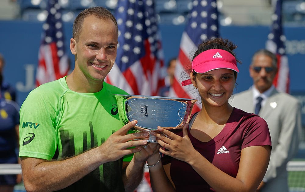 Bruno Soares and Sania Mirza pose for photos with the championship trophy after defeating Abigail Spears and Santiago Gonzalez in the mixed doubles final of the 2014 U.S. Open tennis tournament