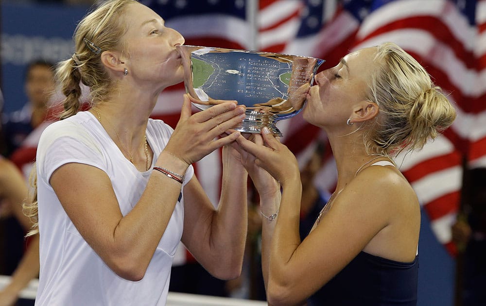 Elena Vesnina, right, and Ekaterina Makarova, of Russia, kiss the championship trophy after winning the women's doubles final over Flavia Pennetta, of Italy, and Martina Hingis, of Switzerland, at the 2014 US Open tennis tournament.