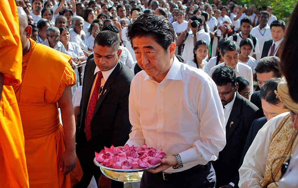 Japanese Prime Minister Shinzo Abe carries flowers as he arrives to offer prayer to a shrine at the Kelaniya Buddhist temple on the outskirts of Colombo, Sri Lanka.