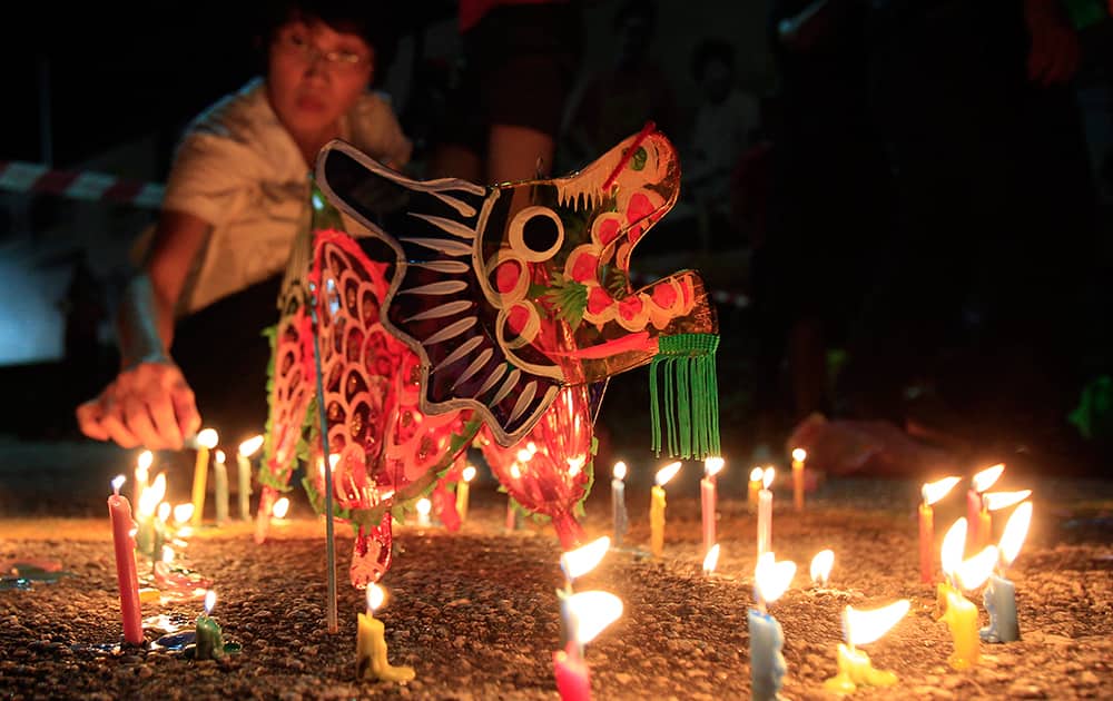 A woman lights a candle next to a dragon-shaped lantern during the Mid-Autumn Festival in Kuala Lumpur, Malaysia.