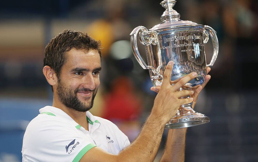 Marin Cilic, of Croatia, holds up the championship trophy after defeating Kei Nishikori, of Japan, in the championship match of the 2014 US Open tennis tournament.