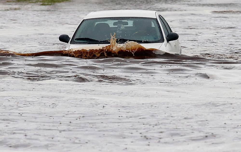 A driver tries to navigate a severely flooded street as heavy rains pour down in Phoenix.