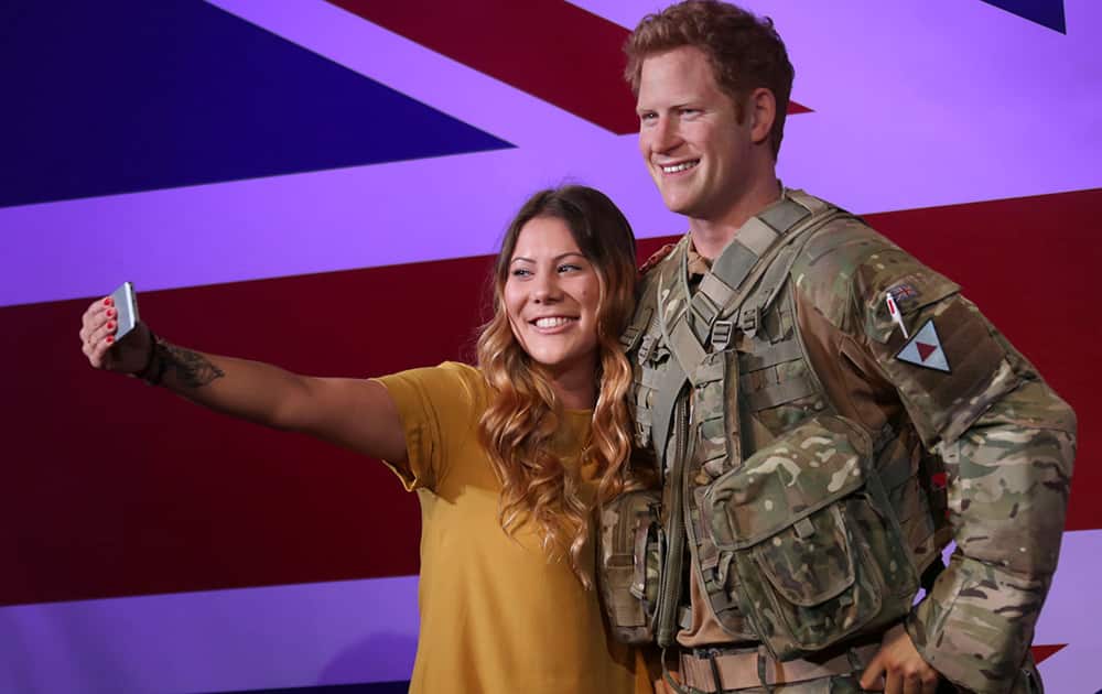 Fan Helen Smith takes a selfie with a new wax figure of Britain's Prince Harry, dressed in army combat fatigues, as it is unveiled at Madame Tussauds in central London, England.