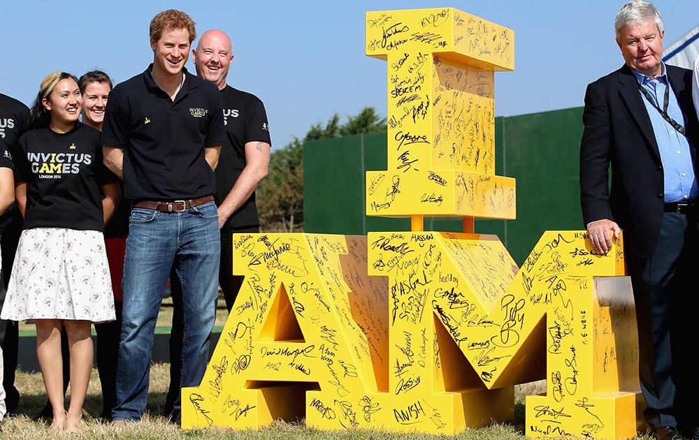 Britain's Prince Harry poses next to a giant Invictus Games logo, signed by volunteers at the driving Challenge, the first event in the Invictus Games, in Gaydon, England.