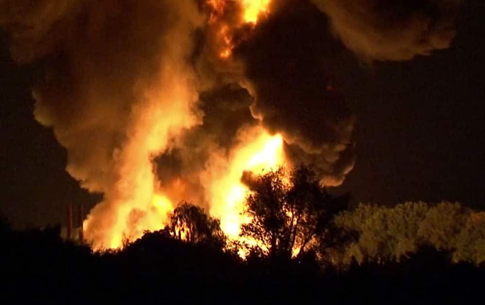 In this image taken from video smoke and flames rise over a chemical waste facility in Ritterhude, Germany. Police said that one person was severely burned in the blast Tuesday night and that the explosion damaged a nearby residential area.