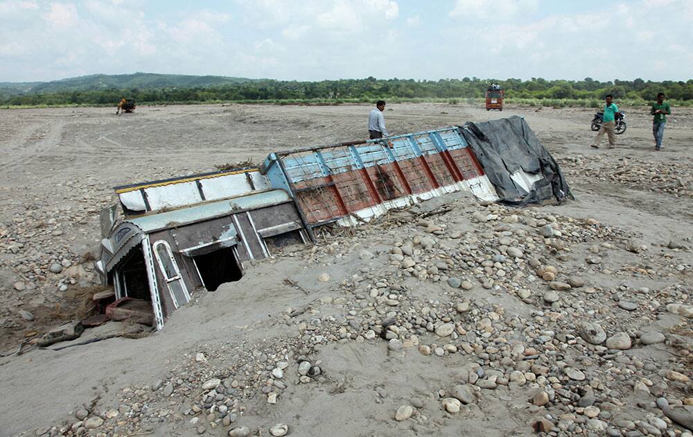 A truck is half-buried in gravel from a landslide caused by flash floods in Akhnoor, about 48 kilometers northwest of Jammu, India.