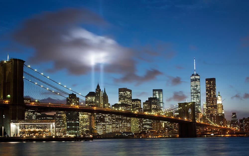 The Tribute in Light rises behind the Brooklyn Bridge and buildings adjacent to the World Trade Center complex, in New York.